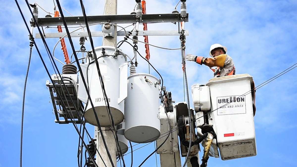 Technicien en panier-élévateur sur une électricité, en haut d'un mât, sous un ciel bleu Technicien en panier-élévateur sur une électricité, en haut d'un mât, sous un ciel bleu