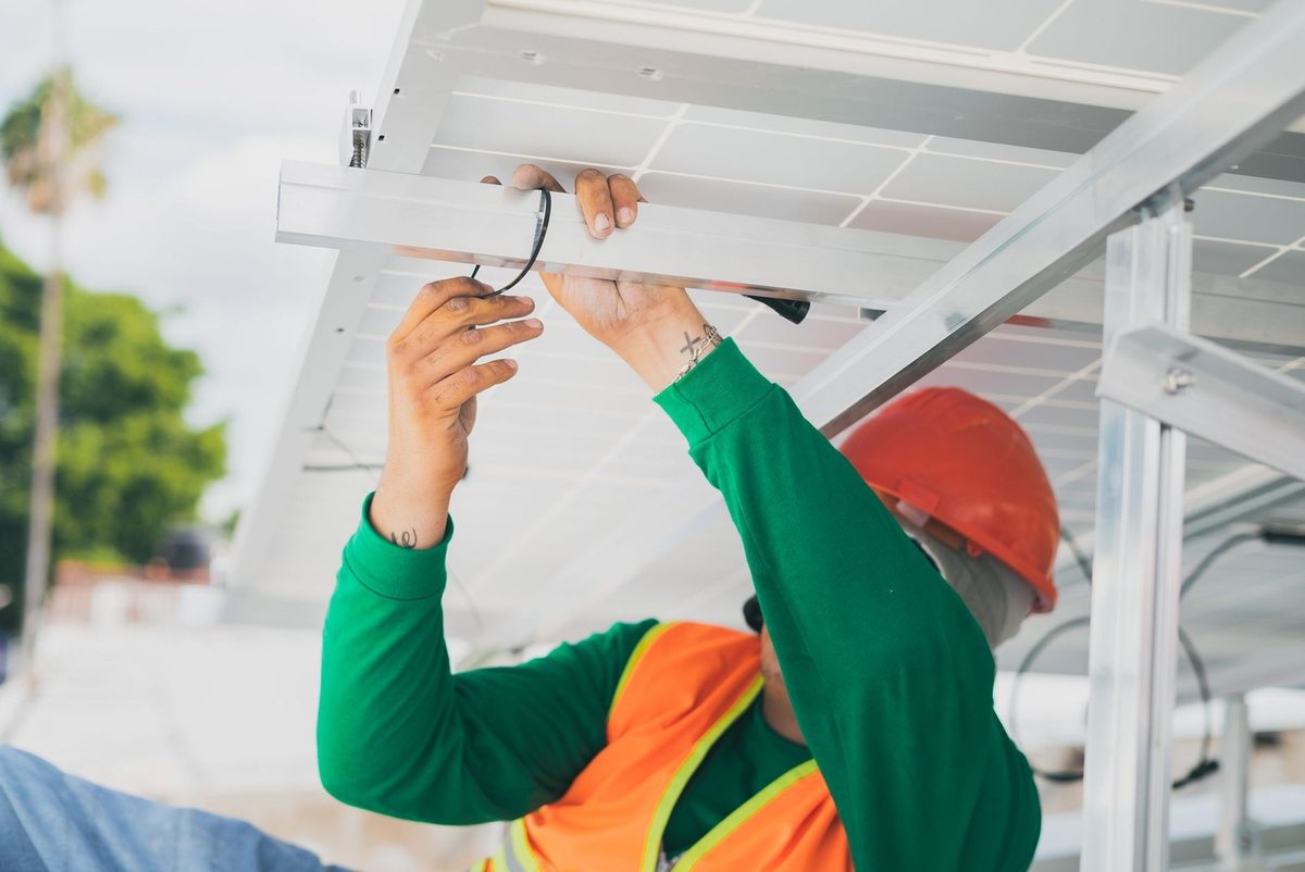 Ouvrier installe des panneaux solaires sur une structure métallique Ouvrier installe des panneaux solaires sur une structure métallique