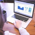 Femme utilisant un laptop avec graphiques et un smartphone sur une table en bois