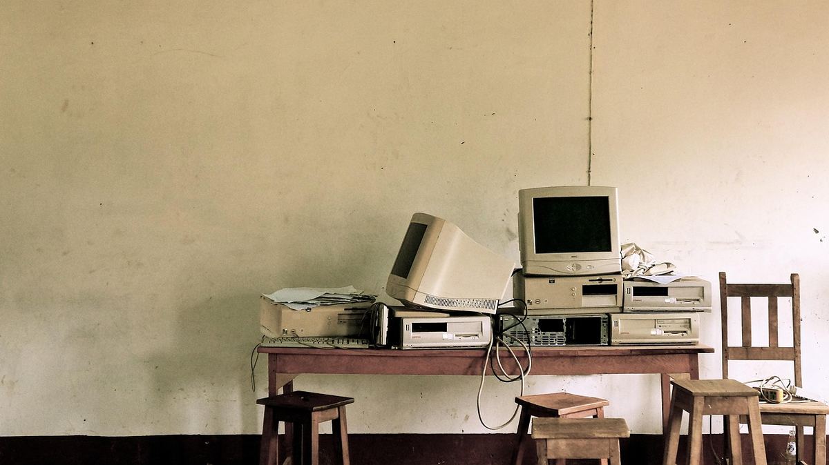 Anciennes machines informatiques empilées sur table, chaises, mur Anciennes machines informatiques empilées sur table, chaises, mur