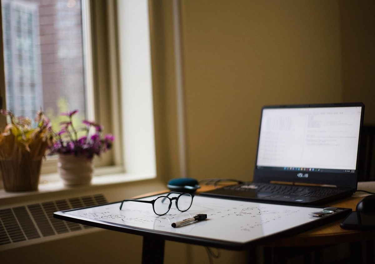 Bureau de travail avec ordinateur portable ouvert, lunettes et papier blanc sur plan de travail Bureau de travail avec ordinateur portable ouvert, lunettes et papier blanc sur plan de travail