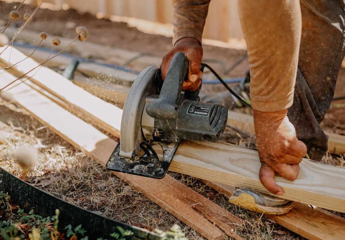 Homme coupant du bois avec une scie circulaire sur une terrasse