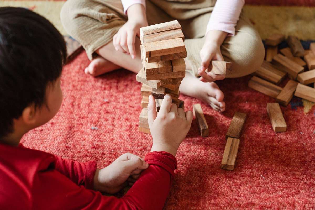 Enfants manipulant des blocs de bois sur un tapis rouge Enfants manipulant des blocs de bois sur un tapis rouge