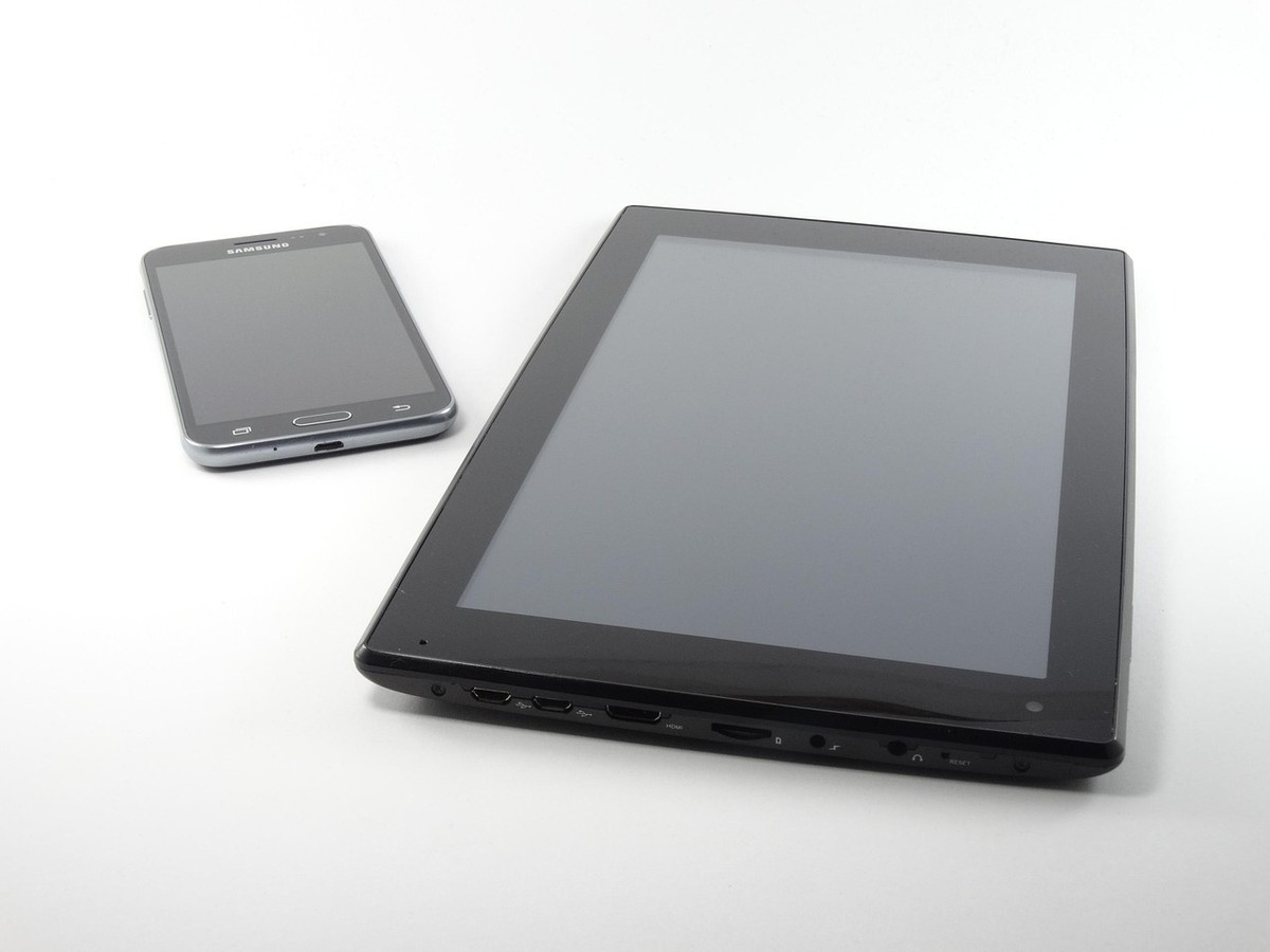 Un smartphone et une tablette noirs posés sur un fond blanc Un smartphone et une tablette noirs posés sur un fond blanc