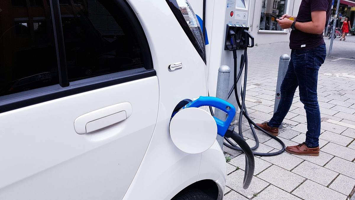 Une voiture électrique se recharge tandis qu'un homme observe Une voiture électrique se recharge tandis qu'un homme observe