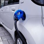 Voiture blanche branchée à un chargeur bleu sur le trottoir
