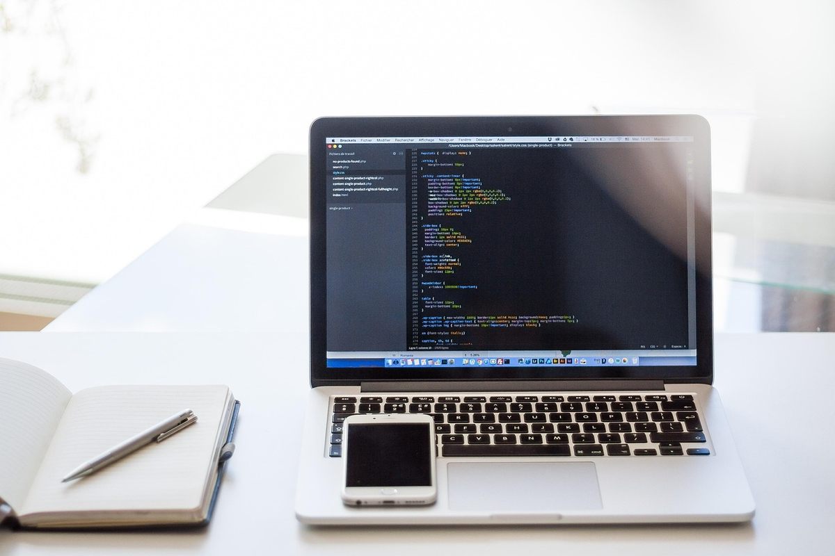 Un ordinateur portable affiche du code sur un bureau blanc Un ordinateur portable affiche du code sur un bureau blanc